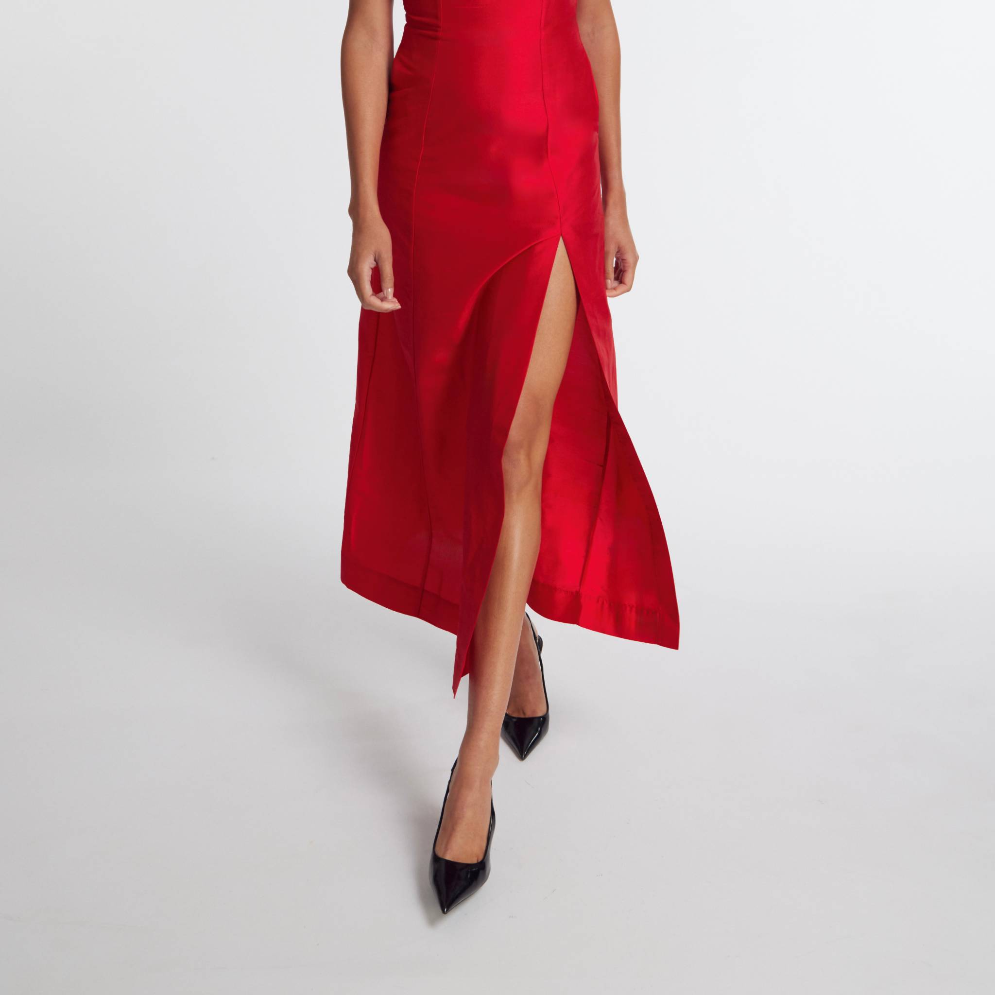 Red dress with a high slit worn by a person on a white background